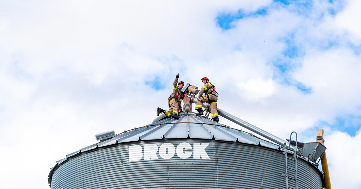First responders wearing PPE on top of a grain bin performing a rescue